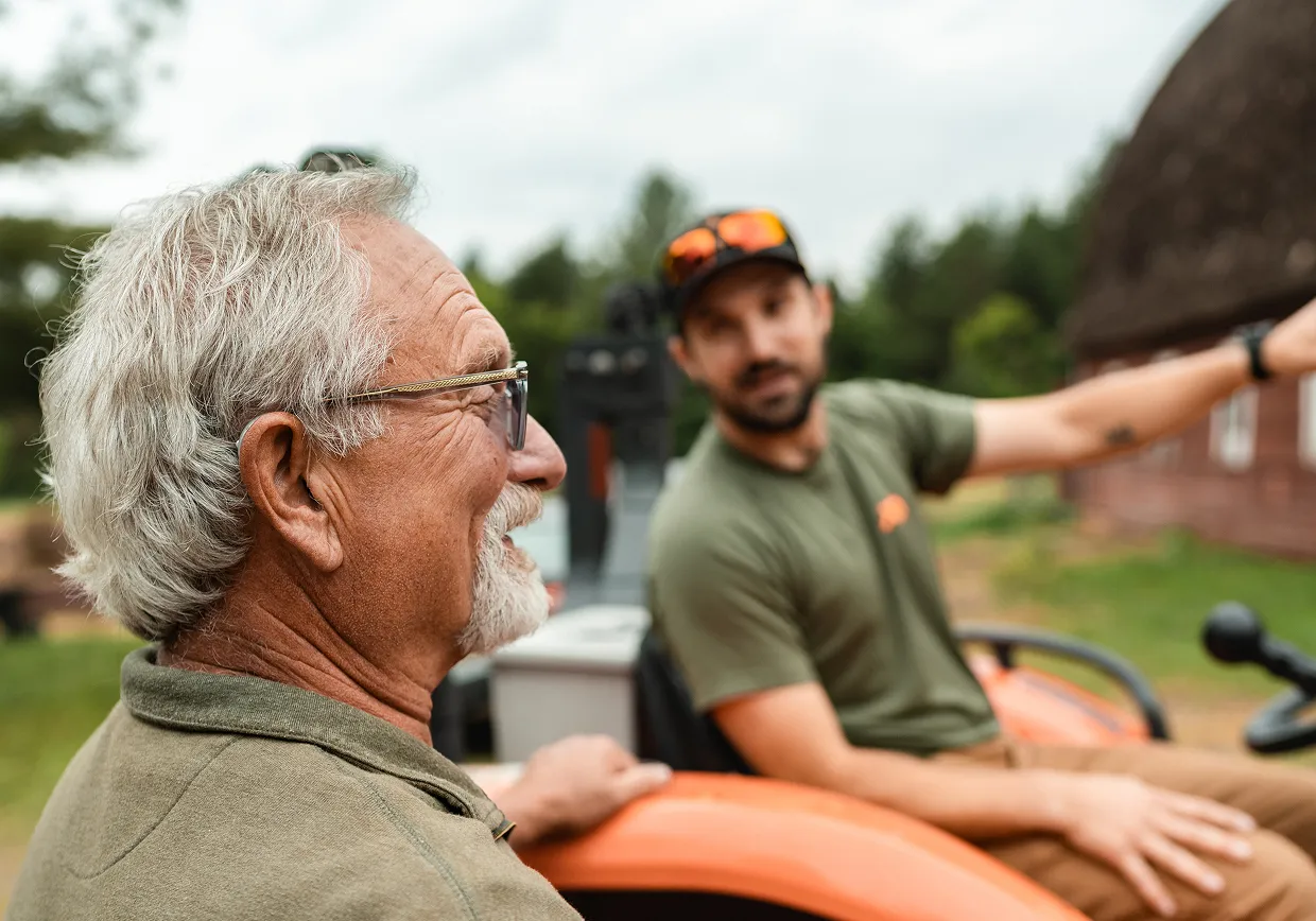 a man standing and talking to another man on a tractor