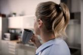 Woman with hearing aid drinks coffee